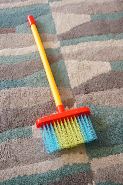 Push broom of several colors put on a multicolored carpet